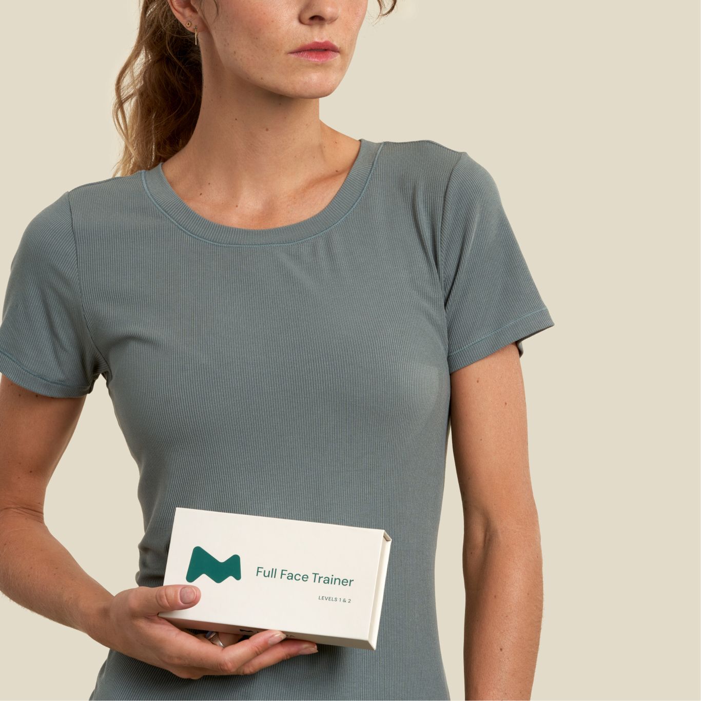 Woman holding a 'Full Face Trainer' box