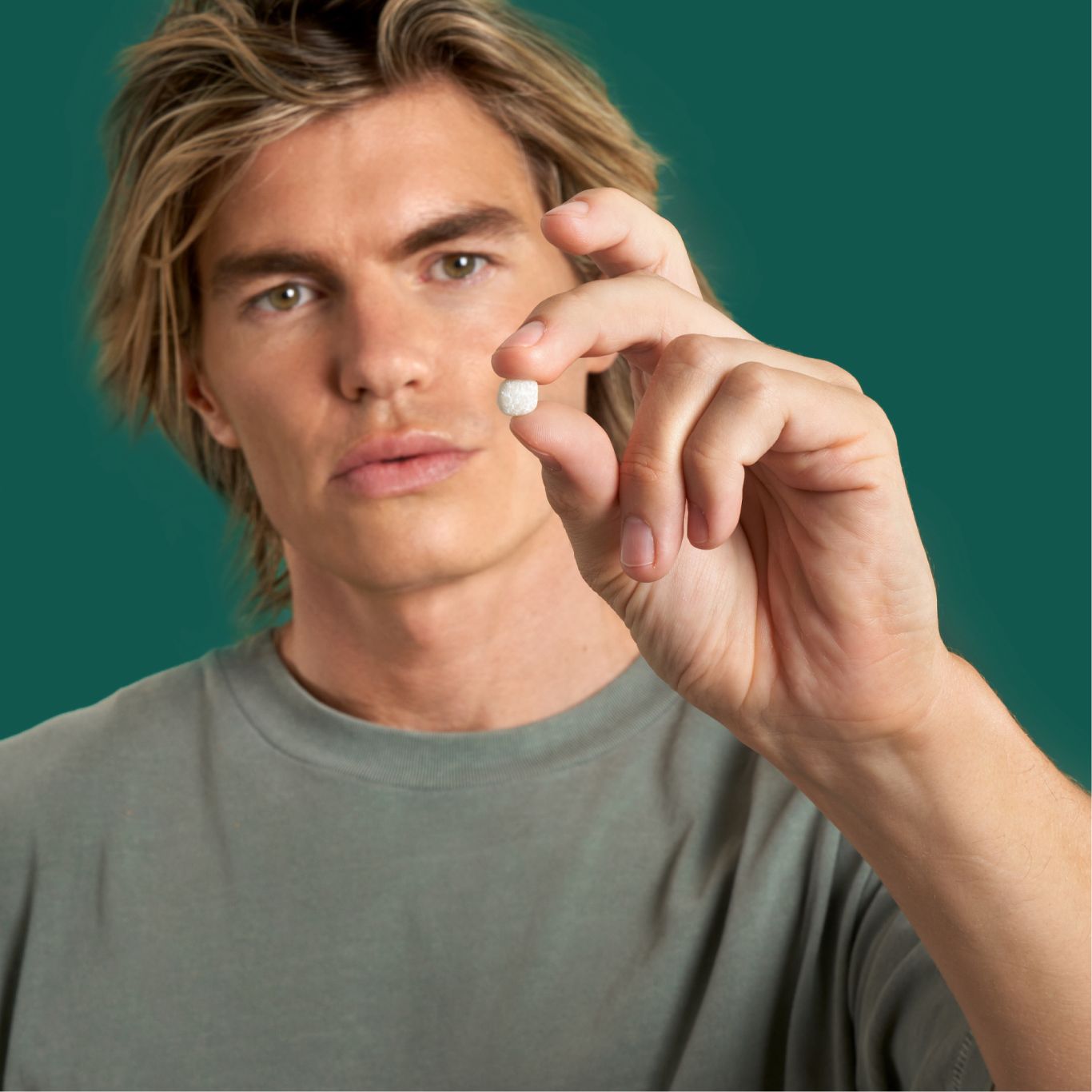 man showing one piece of facial exerciser chewing gum to display the size