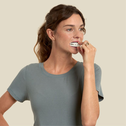 woman has a sand color full face trainer in her mouth