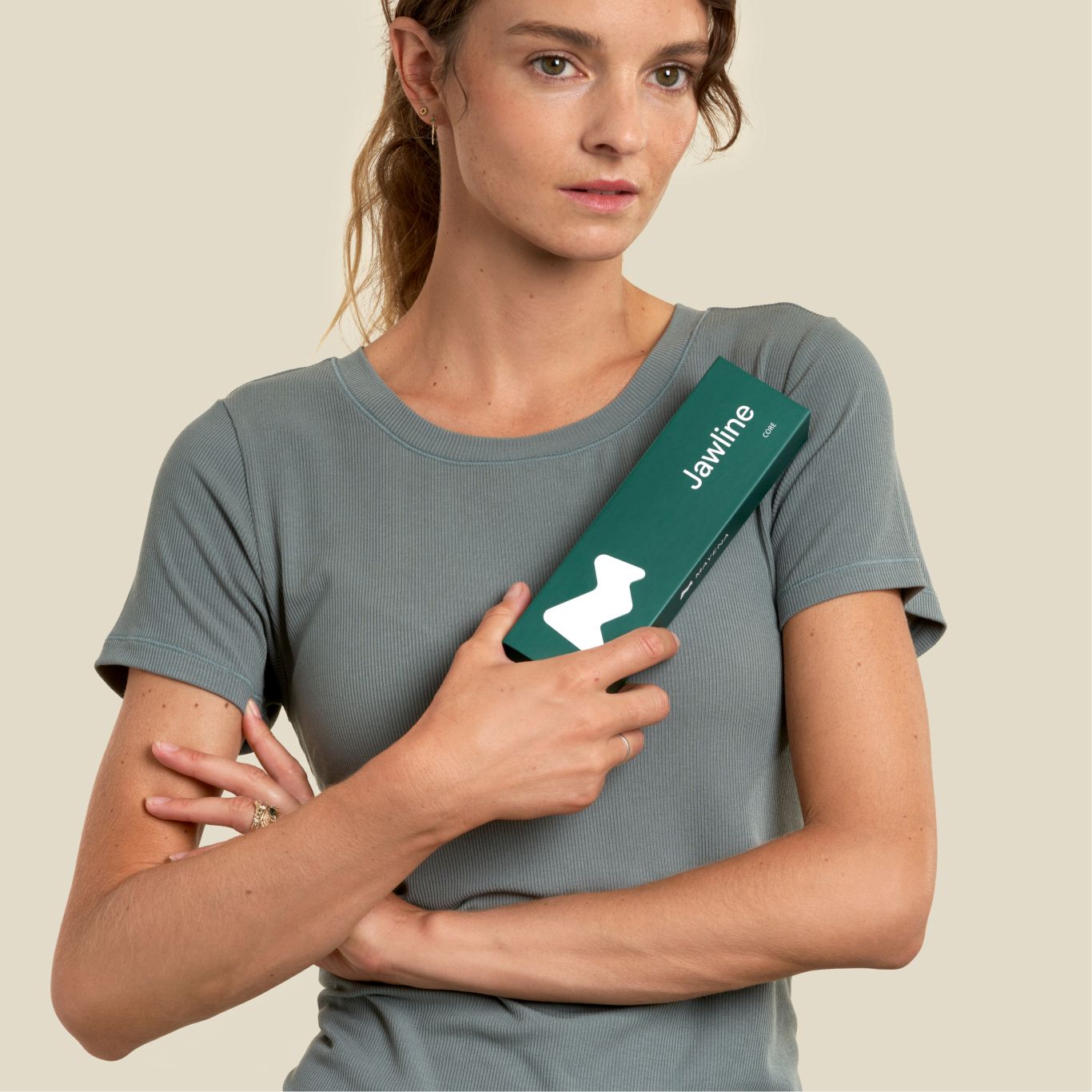 Woman holding jawline core package, has sharp facial features due to mayena exercises